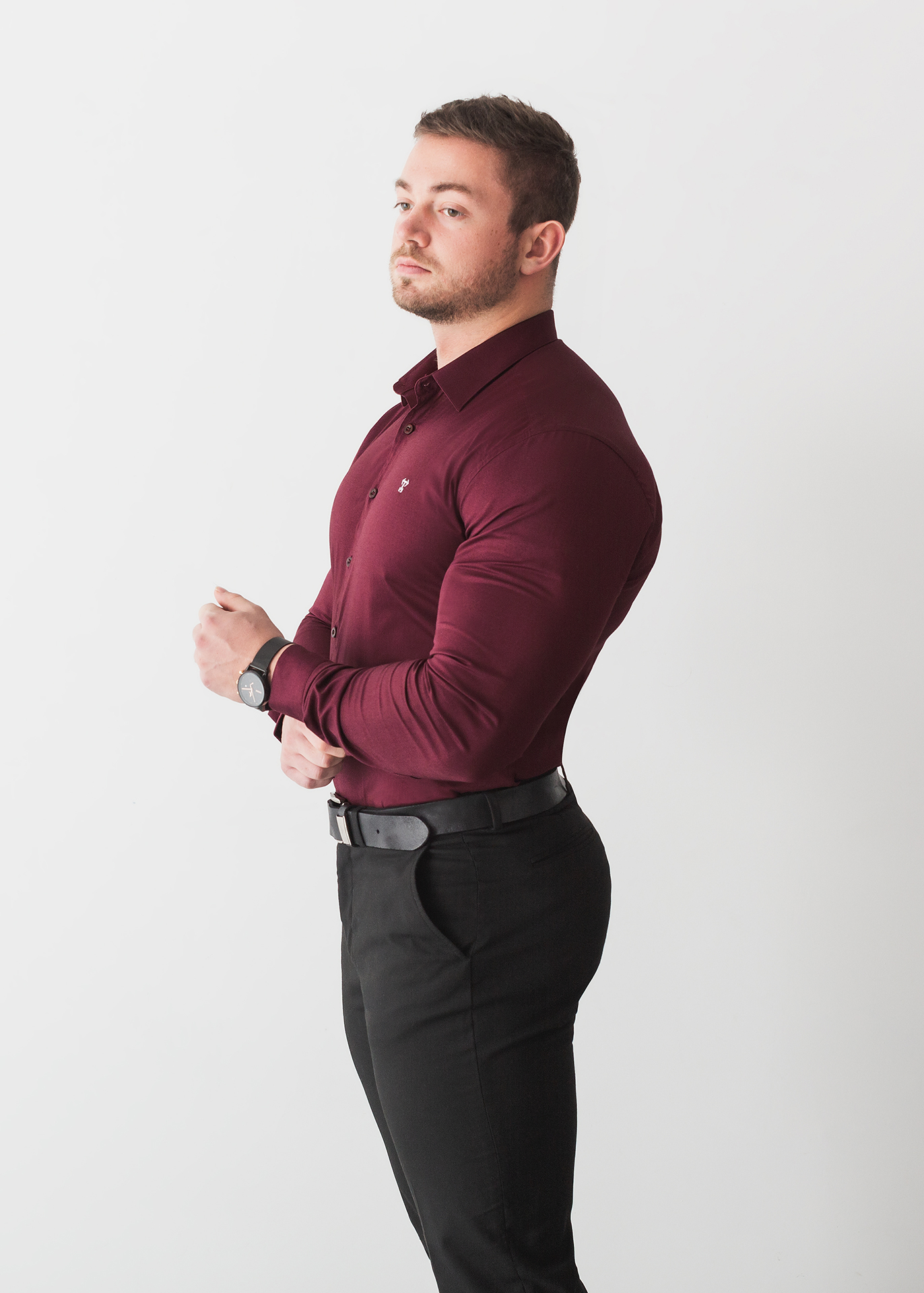 The first of our types of product photography to feature a model. This image shows a muscular male model in a tight-fitting red shirt. The shirt is designed for muscular men, and fits well. He stands at an angle against a white background.