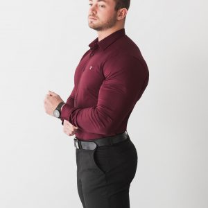 The first of our types of product photography to feature a model. This image shows a muscular male model in a tight-fitting red shirt. The shirt is designed for muscular men, and fits well. He stands at an angle against a white background.