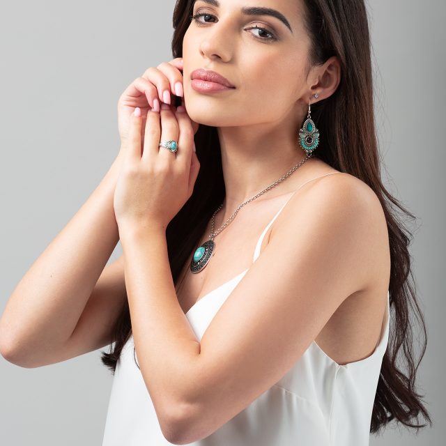 Model photography showing a model wearing a silver jewellery set. The set includes a ring, pair of earrings, and a necklace.