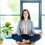 relaxed businesswoman with eyes closed meditating at workplace in office